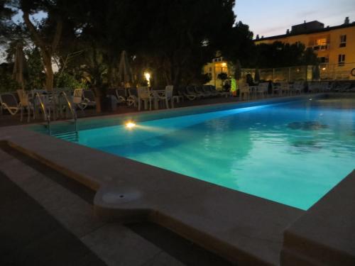 a swimming pool at night with chairs and tables at Hotel Baviera in Cala Ratjada