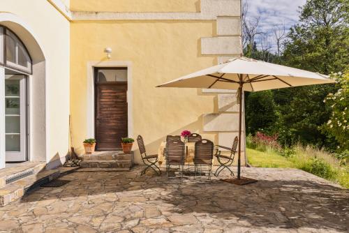 a table and chairs with an umbrella in front of a house at Landhaus im Waldviertel in Zwettl Stadt