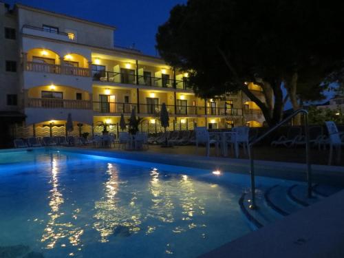a hotel with a swimming pool at night at Hotel Baviera in Cala Ratjada