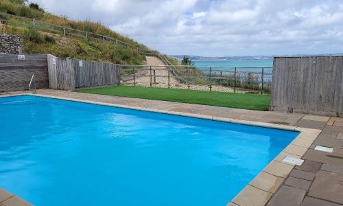 a large blue swimming pool with a wooden fence at Plover 2 - The Cove in Brixham