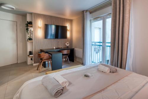 Dormitorio con cama, escritorio y TV en La Parisienne, en Palaiseau