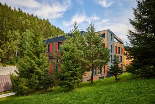 a building on a hill with trees in front of it at Residence Vlčice in Pec pod Sněžkou