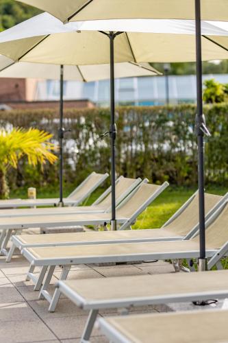 a row of lounge chairs with umbrellas at Kaiser von Österreich, Historik- und Thermalhotel in Bad Radkersburg