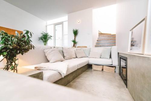 a white living room with a white couch and some plants at Casa Senhorinha in Porto