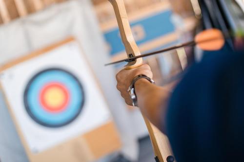 a person holding a bow and arrow in front of a target at Apartmenthaus Wiesenhof in Aschau