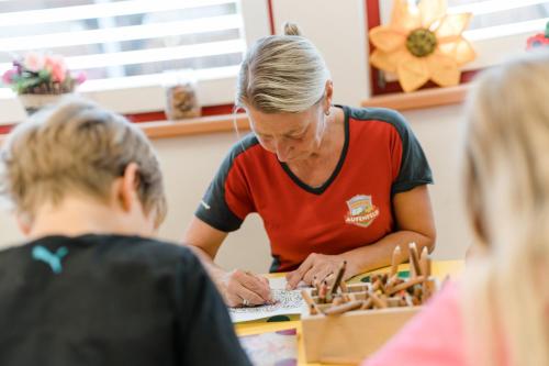 a teacher working with two children in a classroom at Apartmenthaus Wiesenhof in Aschau