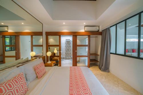 a bedroom with a large white bed and glass walls at Villa Anahata: Modern 2BR Villa w/ Pool in Seminyak ! in Seminyak
