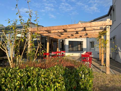 a wooden pergola with red tables and chairs in a garden at ibis Angoulême Nord in Champniers