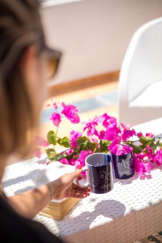 a woman sitting at a desk with a coffee mug and flowers at ILIDI Rock in Livadia