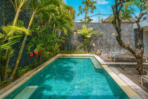 a swimming pool in the backyard of a house with palm trees at Villa Anahata: Modern 2BR Villa w/ Pool in Seminyak ! in Seminyak