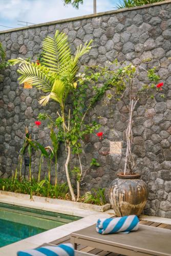 a vase sitting on a table next to a pool at Villa Anahata: Modern 2BR Villa w/ Pool in Seminyak ! in Seminyak