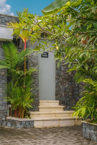 a stone building with a white door and some trees at Villa Anahata: Modern 2BR Villa w/ Pool in Seminyak ! in Seminyak
