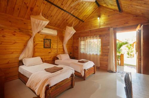 una camera con 2 letti in una cabina di legno di Zen Cottages ad Agonda