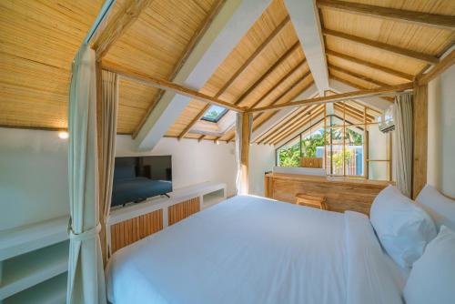 a bedroom with a white bed and a tv at Villa Tiny - Romantic A-Shape 1BR Villa Close to Nyanyi Beach in Tanah Lot