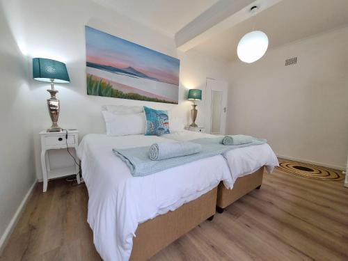 a bedroom with a large bed with a painting on the wall at Palmview House in Hermanus