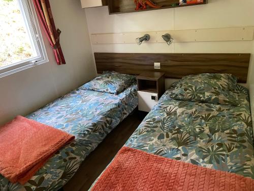 a small room with two beds and a window at Mobile Home Chalet luxe in Saint-Chéron