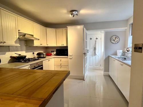 cocina con armarios blancos y encimera de madera en The Windmill en Busheyheath