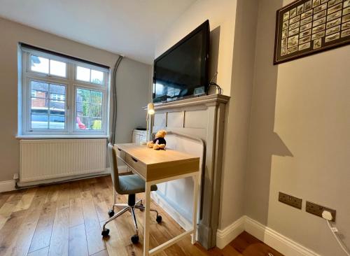 a room with a desk and a tv on a wall at The Windmill in Busheyheath