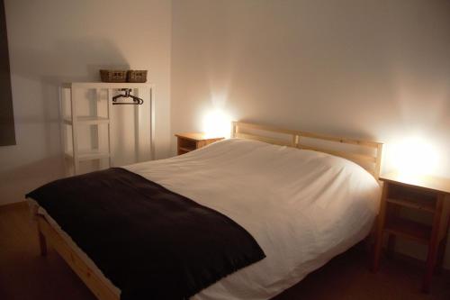 a bedroom with a white bed and two lights on two tables at Gîte du Lac Cosy in Fosses-La-Ville