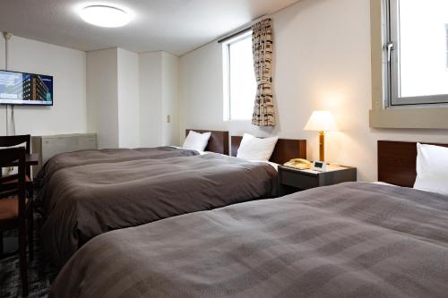 a hotel room with two beds and a window at Kurashiki Station Hotel in Kurashiki
