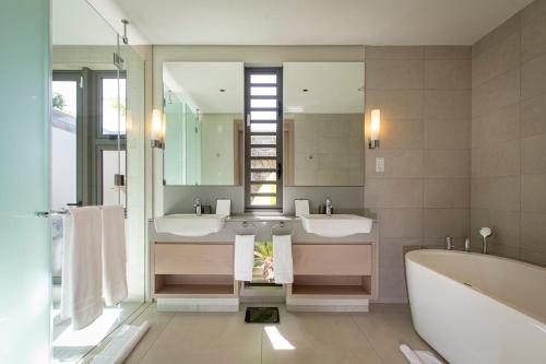 bagno con 2 lavandini, vasca e specchio di Villa Luxe Anahita Ile Maurice a Beau Champ
