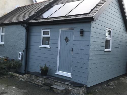 a blue house with a door and a window at Traeth Arian Cottage in Benllech