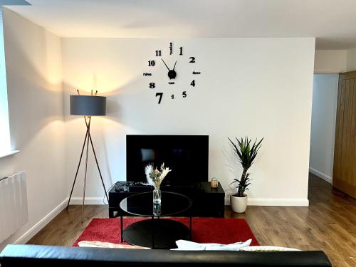 a living room with a table and a clock on the wall at Captivating 2-Bed Apartment in Bedford in Bedford