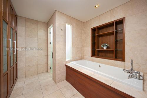 a bathroom with a tub and a sink and a window at Tran Beach Front Luxury Villa in Danang