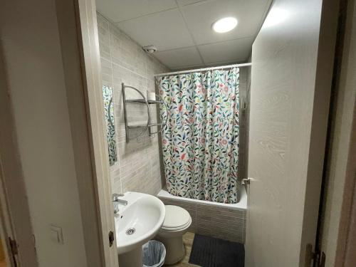 a bathroom with a sink and a toilet and a shower curtain at Pensión La Estrella in Zaragoza