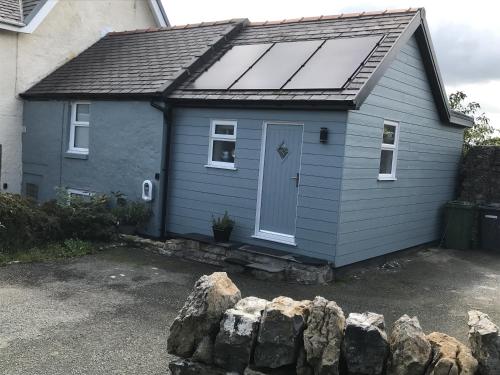 a small blue house with a solar roof at Traeth Arian Cottage in Benllech