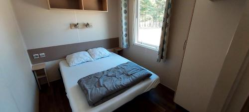 Habitación pequeña con cama y ventana en Camping Les Sirènes, en Castellane