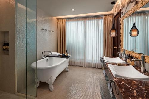 a bathroom with two sinks and a bath tub at Hotel de l'Opera Hanoi - MGallery in Hanoi