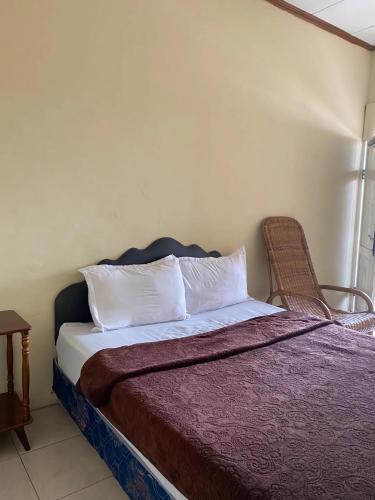 a bedroom with a bed and a chair next to it at RON'S Guest House Berastagi in Berastagi