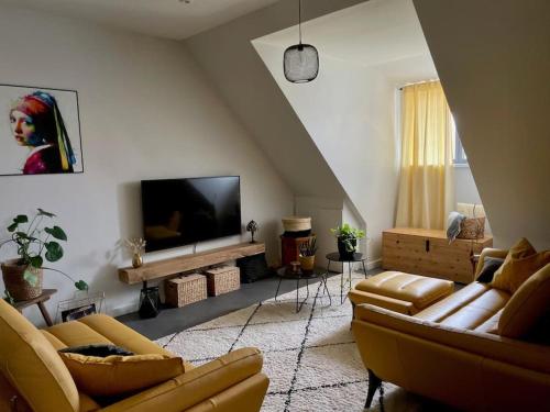 a living room with couches and a flat screen tv at La Grange des Duc(s) in Eckbolsheim