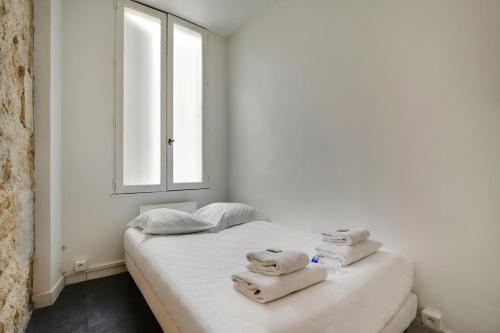 - une chambre blanche avec un lit et des serviettes dans l'établissement CMG Louis Blanc - Gare de l'Est, à Paris