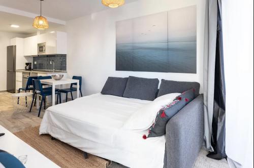 Un dormitorio con una cama blanca y una cocina. en Los Alamos de Cotillo, en Cotillo