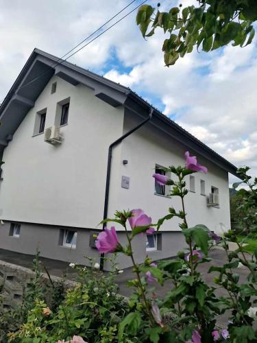 a white house with purple flowers in front of it at Aparthouse Jana Breg in Žirovnica
