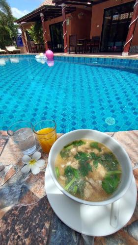 a bowl of soup on a table next to a swimming pool at Panisara Pool Villa Resort Huahin in Hua Hin