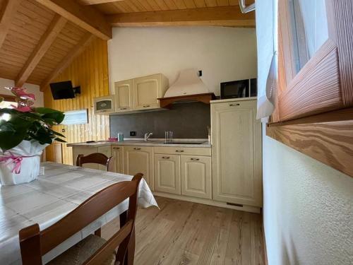 a kitchen with white cabinets and a table and a sink at Orobie Holiday Apartments in Albosaggia