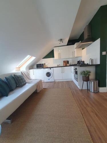 uma sala de estar com um sofá e uma cozinha em Loft Apartment near Harry Potter Coaches em Watford