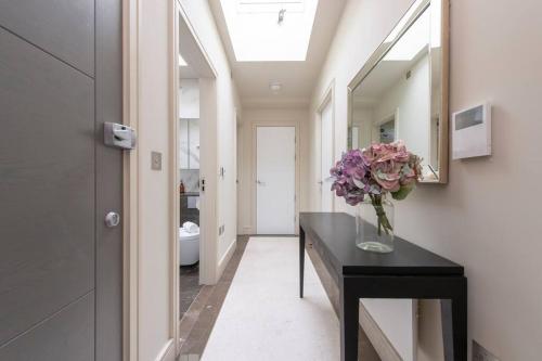 a bathroom with a table with a vase of flowers on it at Chigwell 1BR + Study Escape in Chigwell