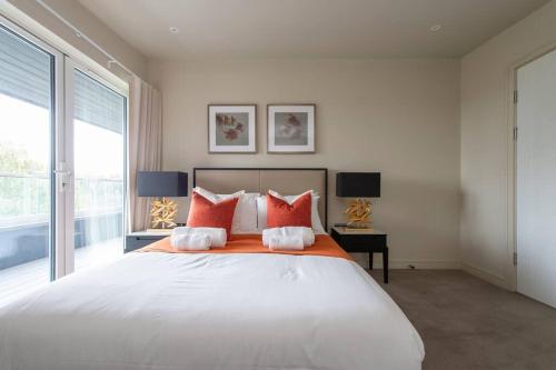 a bedroom with a large white bed with red pillows at Chigwell 1BR + Study Escape in Chigwell