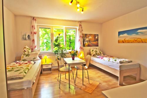 Cette chambre comprend 2 lits, une table et une fenêtre. dans l'établissement Ferienwohnung KAKADU Apartment Dresden Laubegast WLAN TV Fahrrad, à Dresde