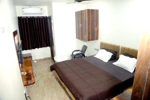 a bedroom with a bed with a brown blanket and white pillows at Hotel Kiwi Inn in Indore