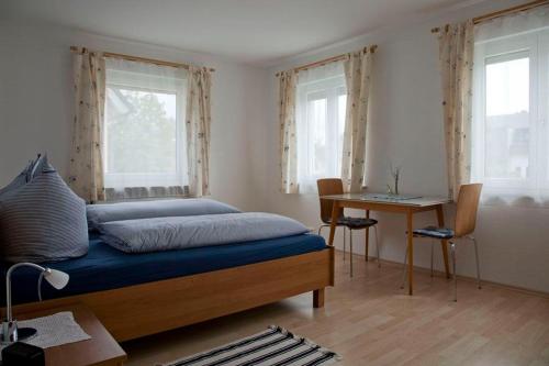 a bedroom with a bed and a desk and windows at Haus Josefine in Friedrichshafen