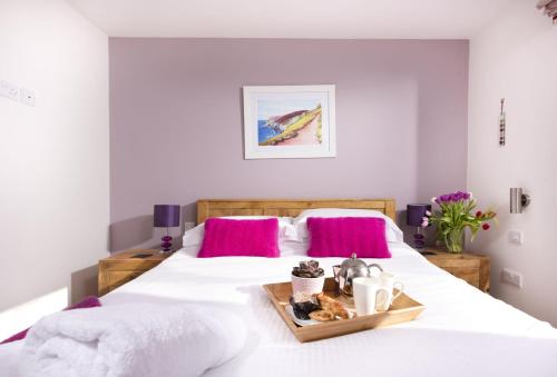 a bedroom with two beds with white sheets and pink pillows at Triskel in St. Agnes 