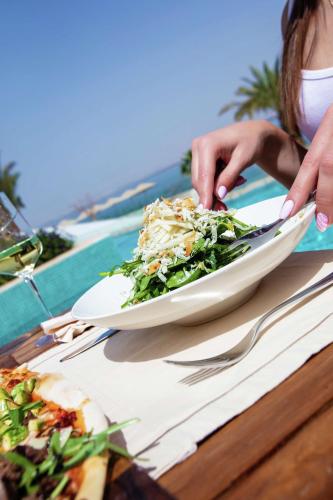a woman sitting at a table with a plate of food at Hilton Dead Sea Resort & Spa in Sowayma