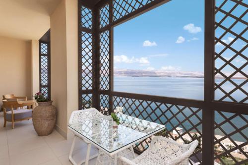 a balcony with a table and chairs and a view of the water at Hilton Dead Sea Resort & Spa in Sowayma