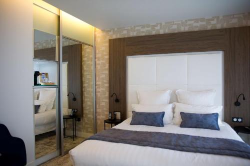 a bedroom with a large white bed with blue pillows at Le Grand Hôtel Grenoble, BW Premier Collection by Best Western in Grenoble