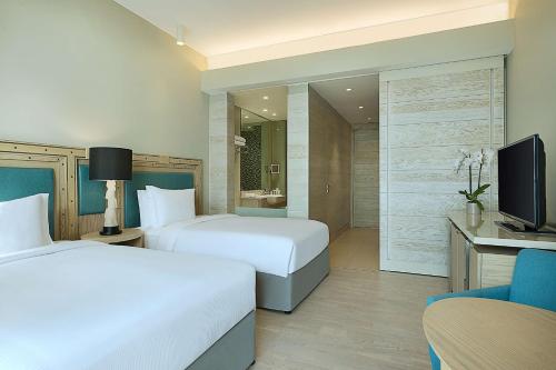 a hotel room with two beds and a television at Hilton Dead Sea Resort & Spa in Sowayma